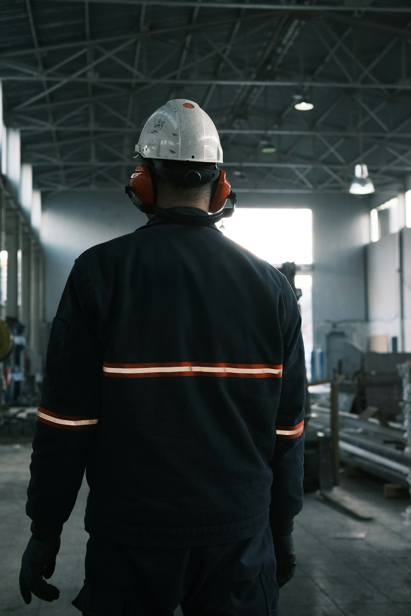 Trabajador con chaqueta técnica con cinta reflectante en planta industrial